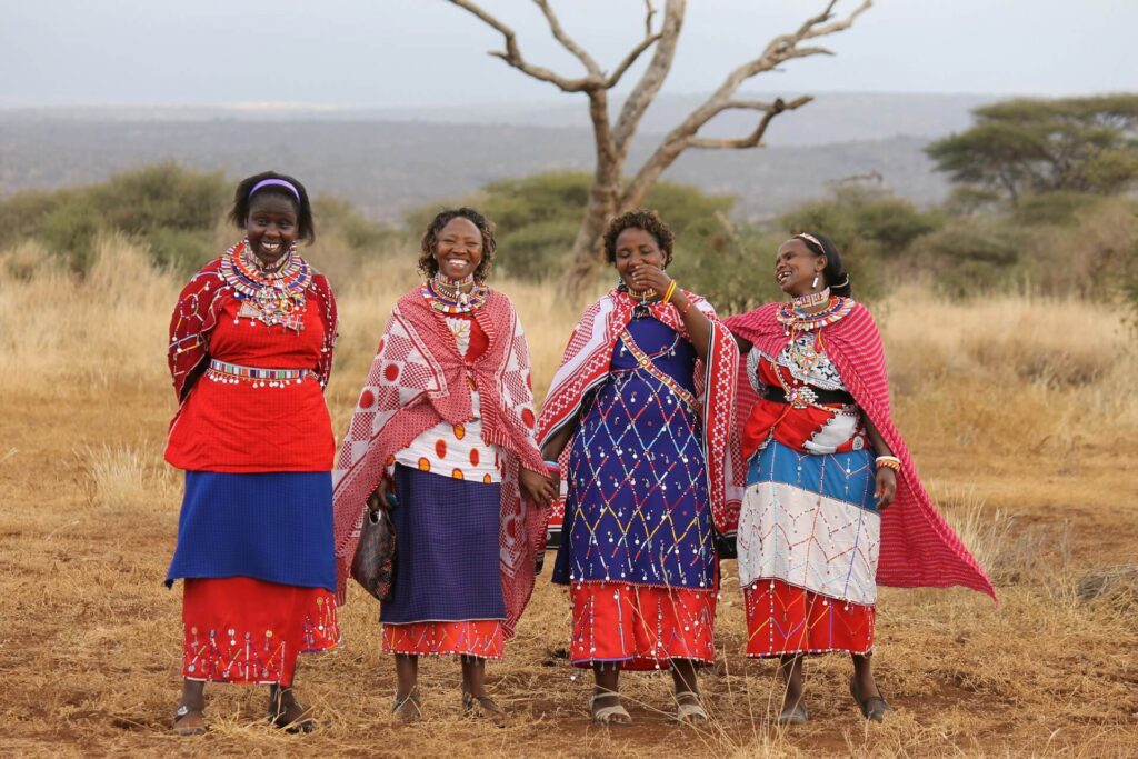 Maasai women in colorful clothes standing in a field.